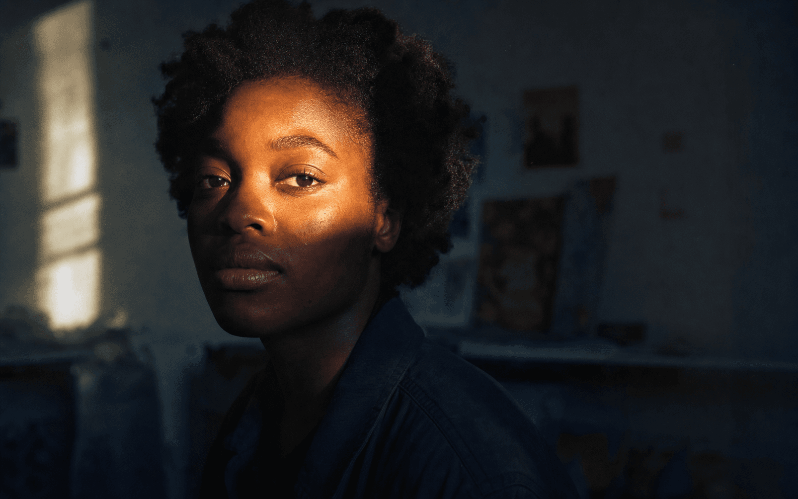 A Black woman illuminated by warm sunlight in a creative studio