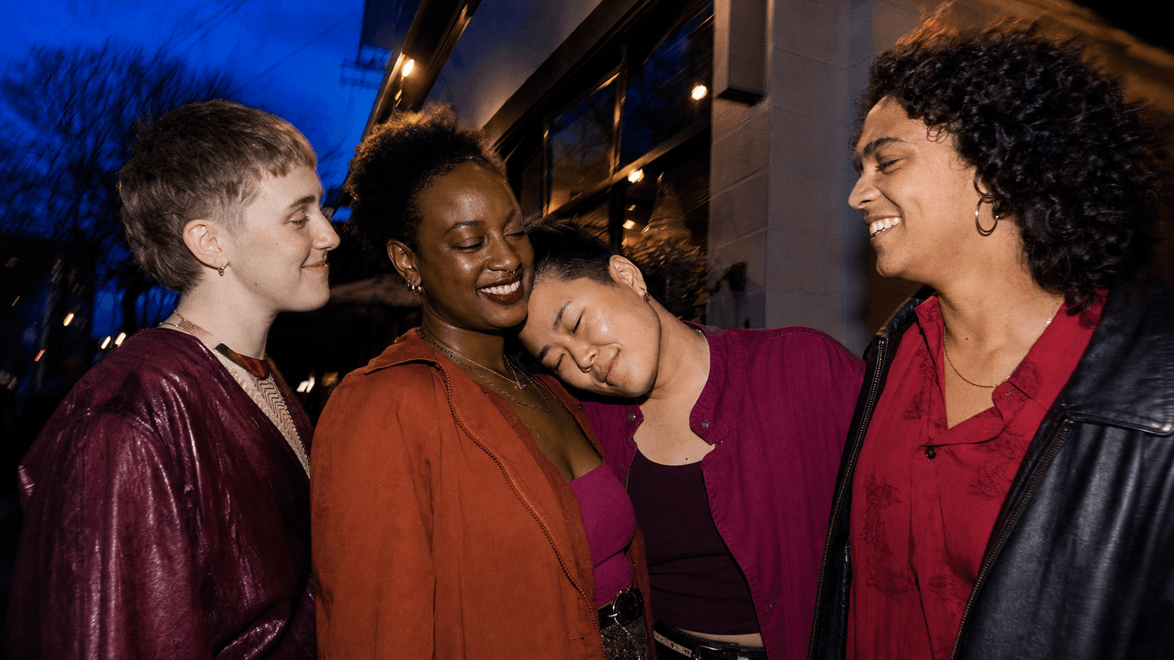 Queer friends sharing a warm moment outside a community arts venue